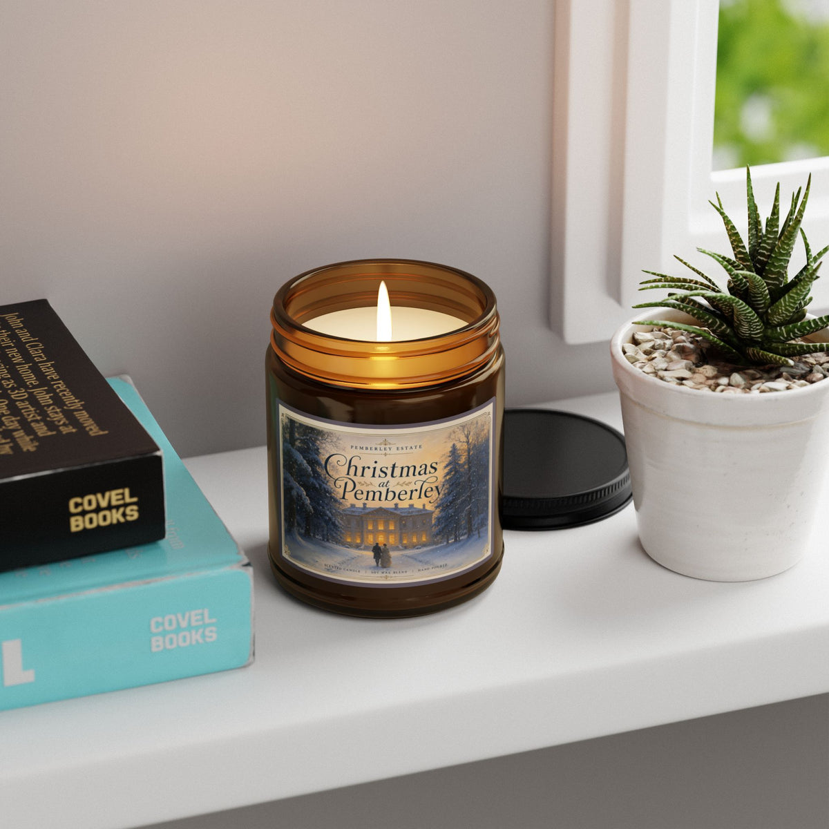 Candle in a jar with a printed design on a shelf with books and a plant