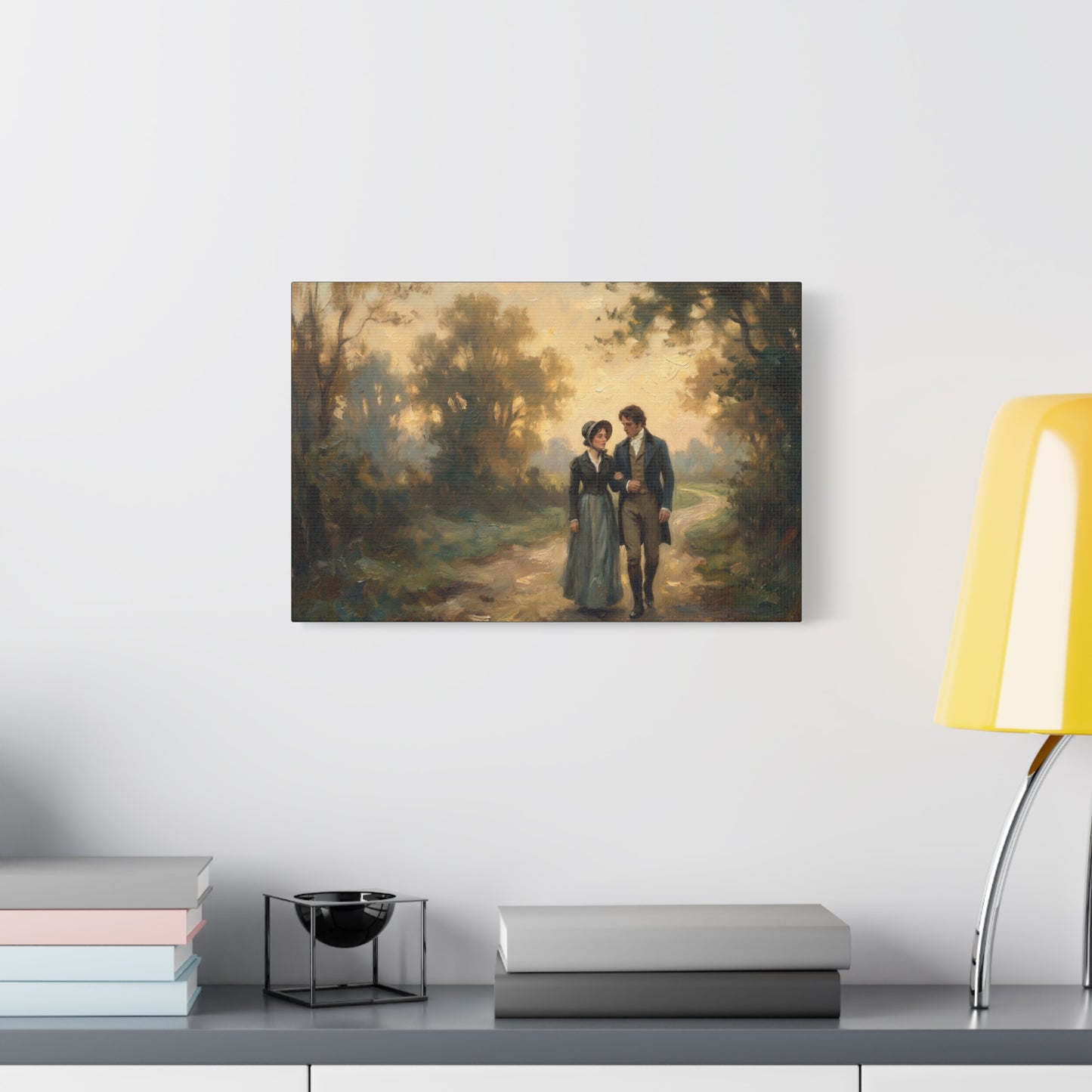 Framed painting of a couple walking in a forest on a wall above a desk with books and a lamp.