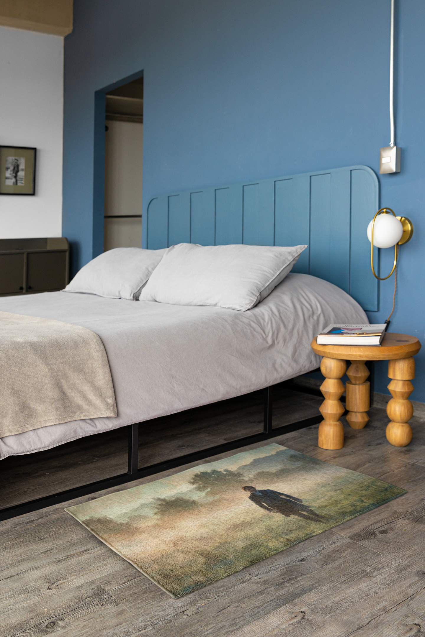 Bedroom with blue walls, a bed with white bedding, and a wooden side table.